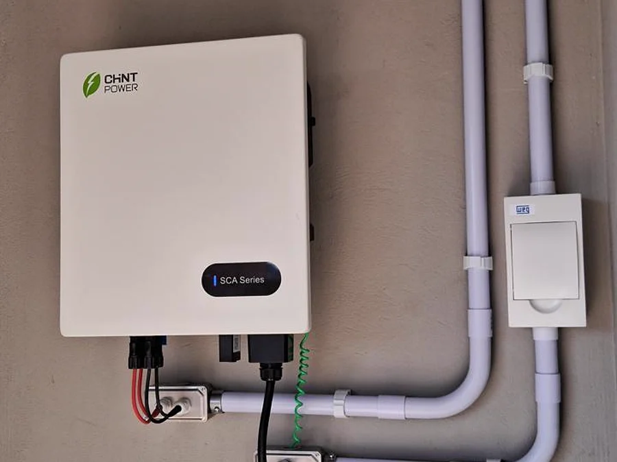 Inversor solar instalado em parede, com infraestrutura aparente organizada.